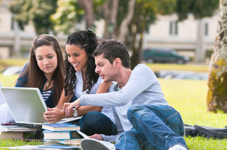 three students viewing a laptop computer screen